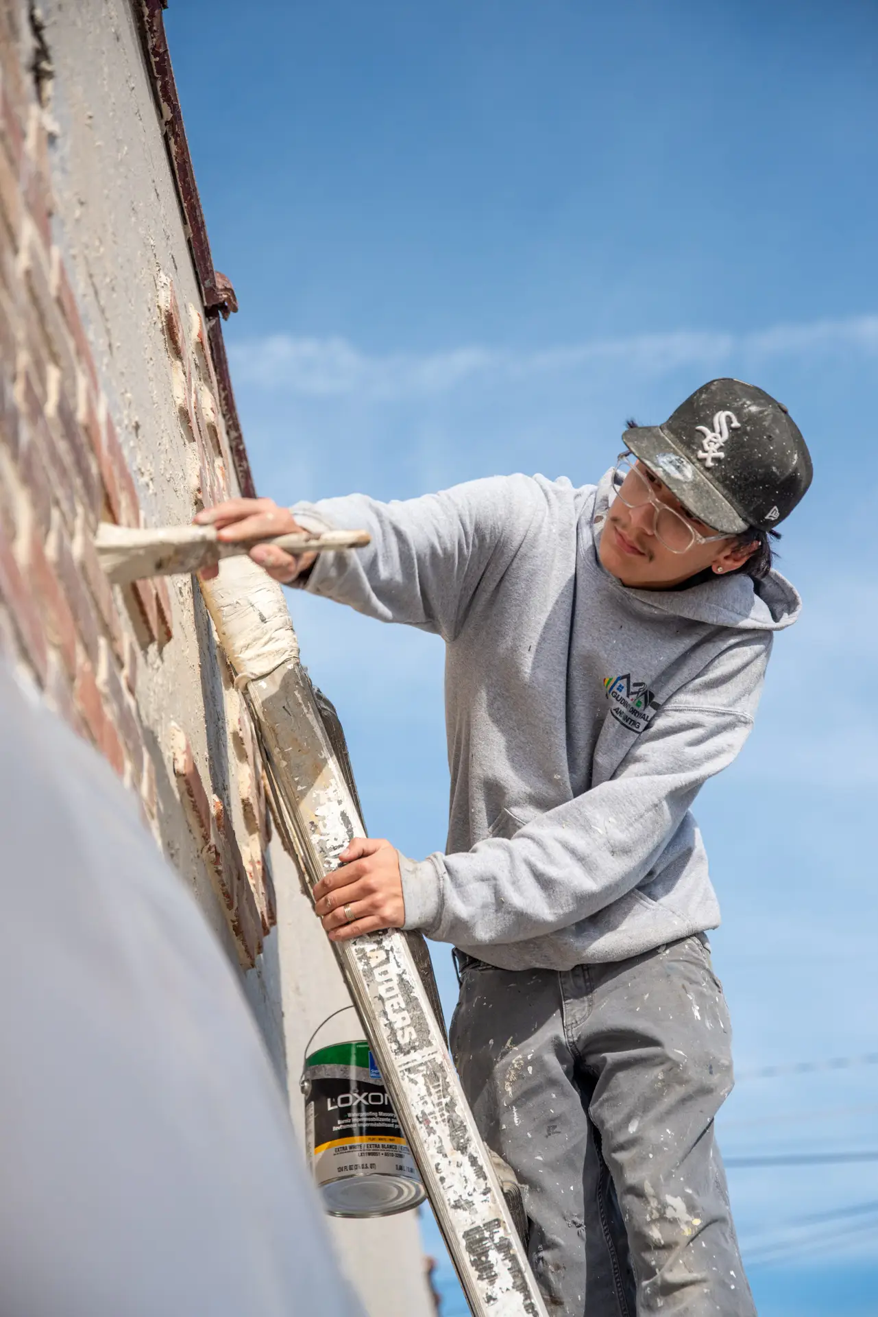 Young man painting side of brick building
